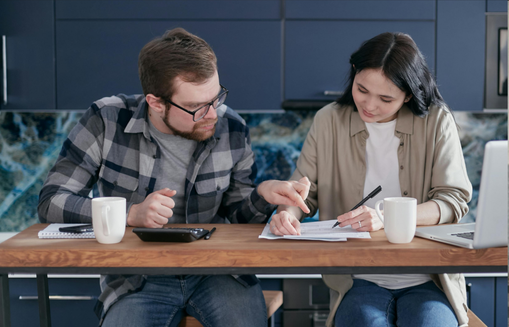 Two person working on a laptop in a home office with a coffee