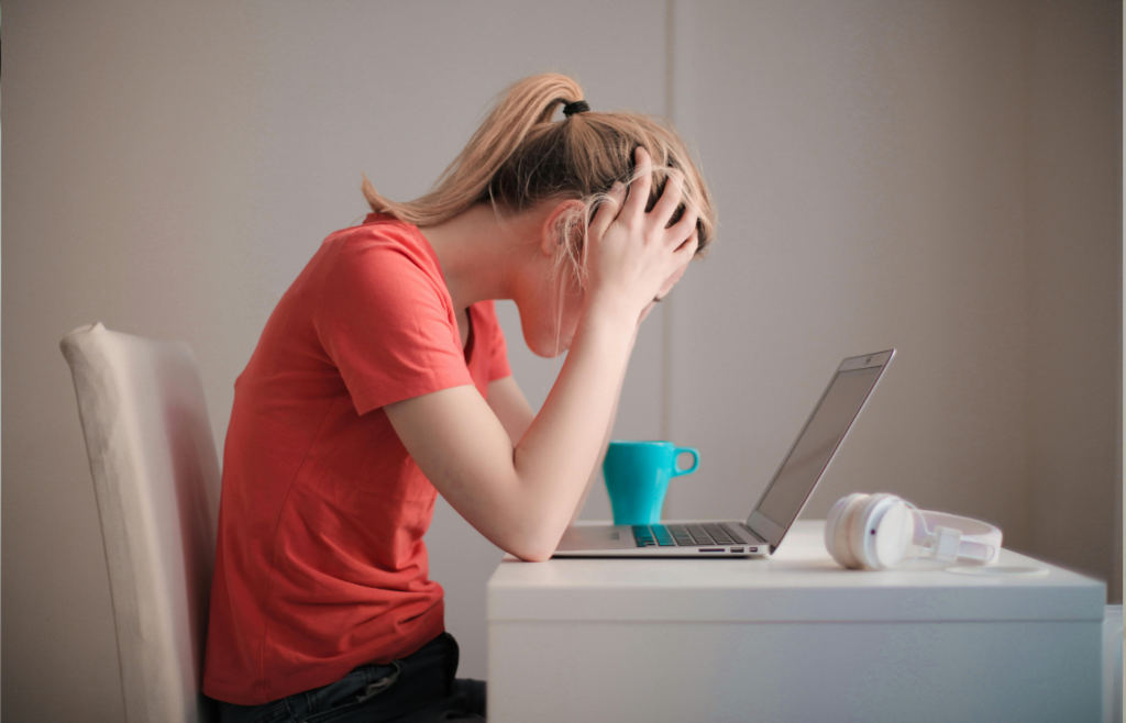 A person meditating at a desk with a laptop