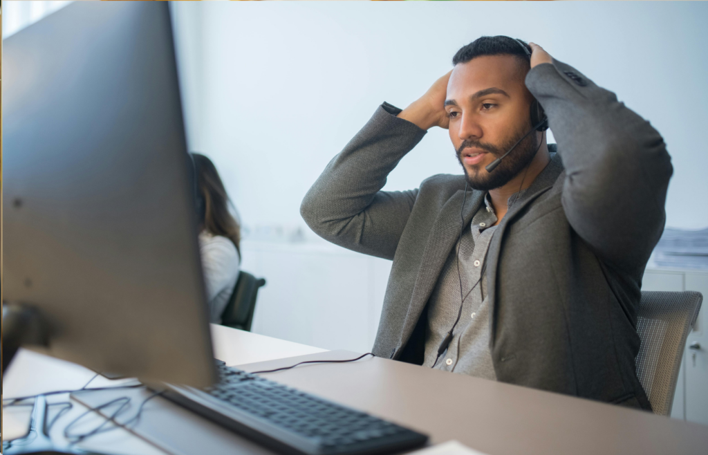 A person looking exhausted at their desk with their head in their hands