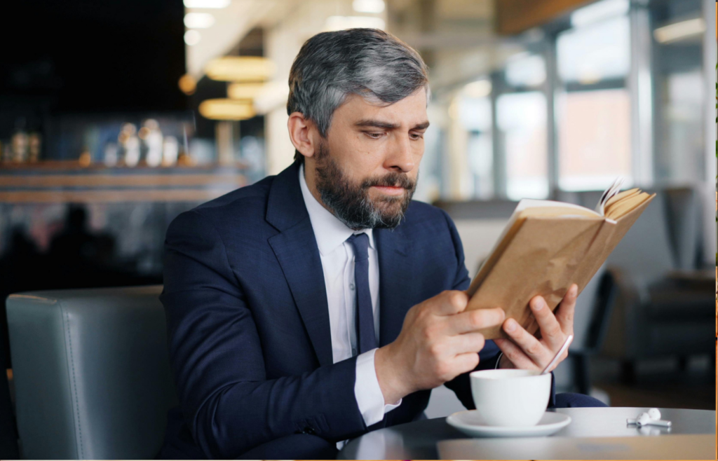 A professional reading a book in a coffee shop