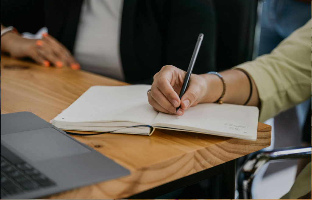 A professional jotting notes in a notebook during a meeting