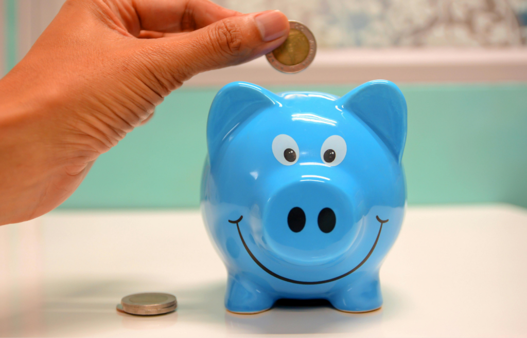 A person stuffing cash into a piggy bank.