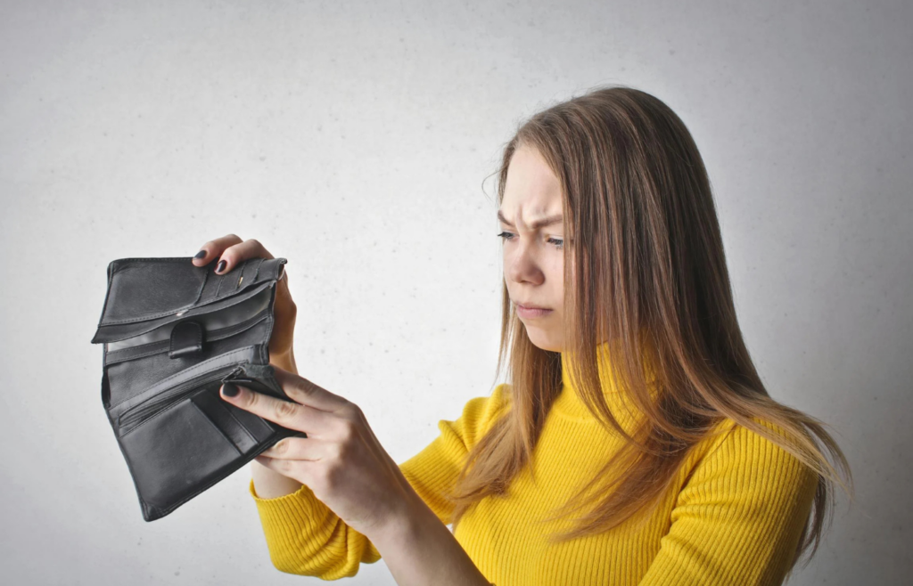 An employee holding an empty wallet while looking at a paycheck