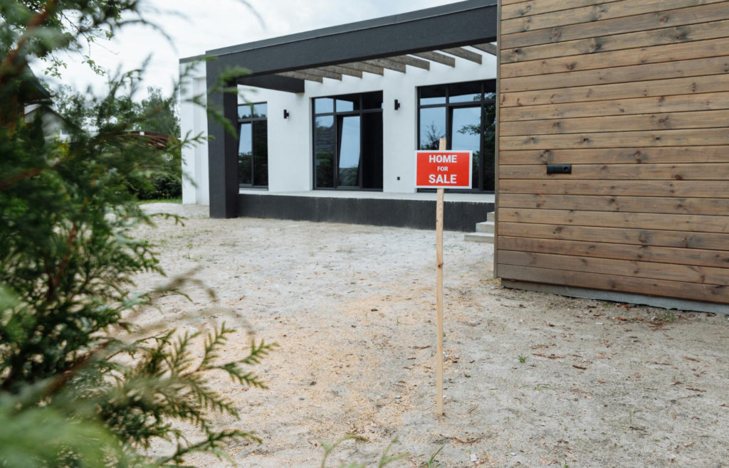 A modest home with a "For Sale" sign indicating affordability