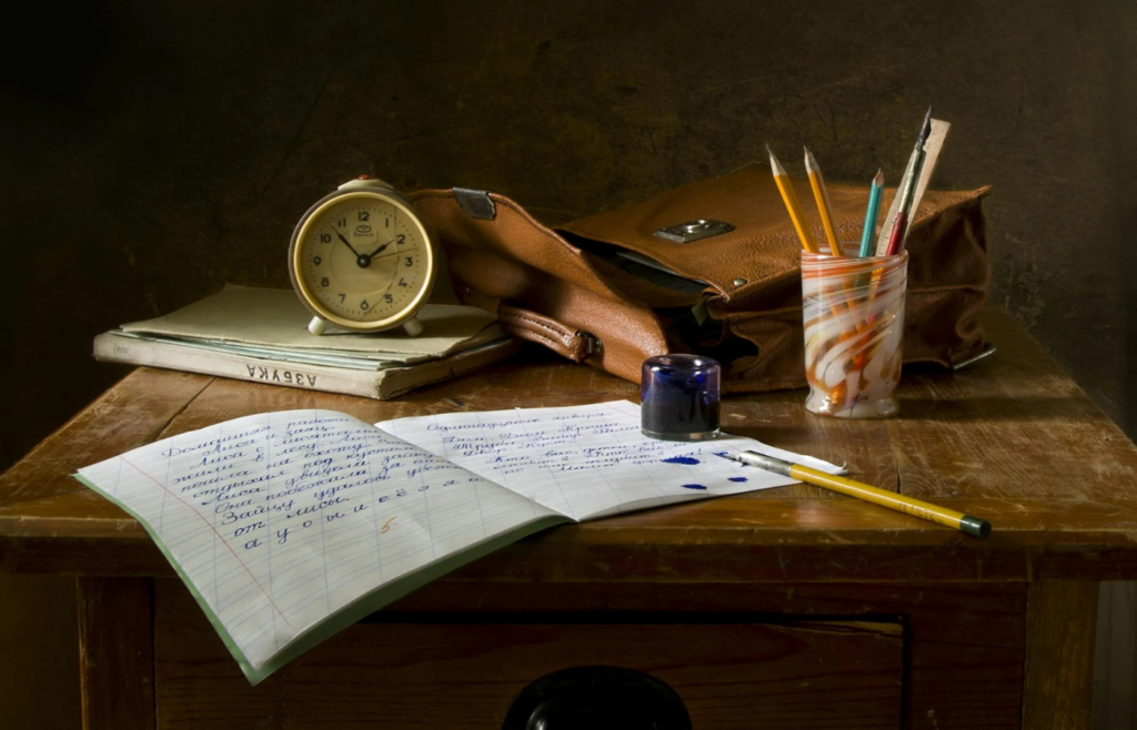 A cluttered desk with unfinished projects and a clock showing time passing