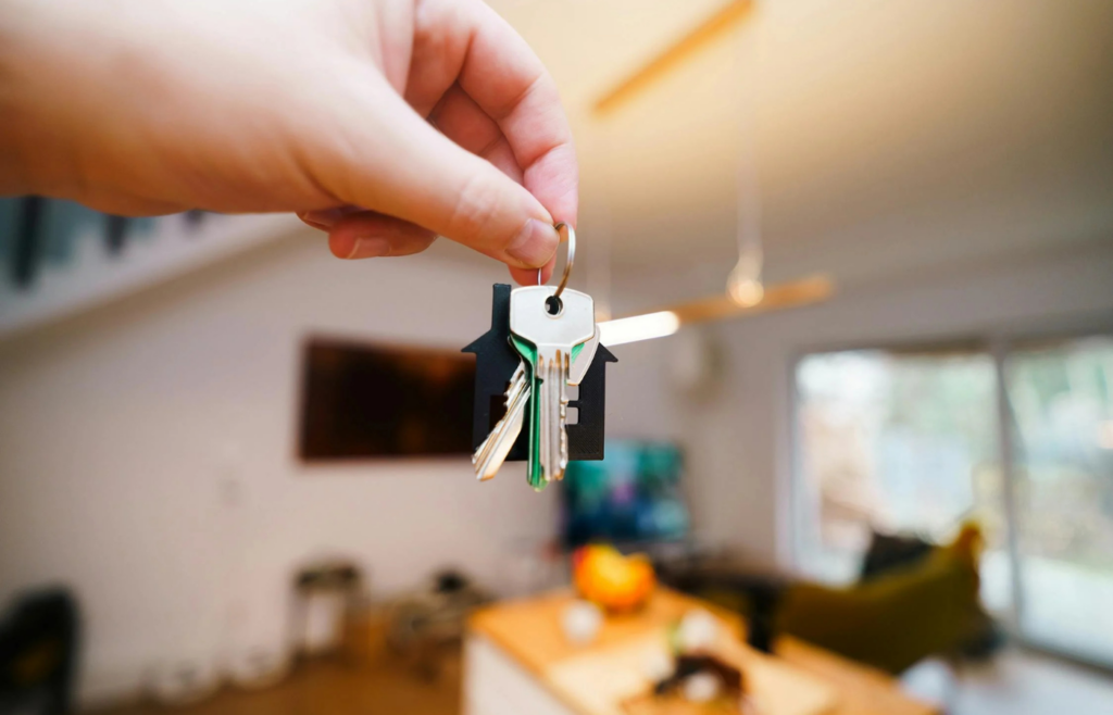 A retiree holding keys in front of a rental property