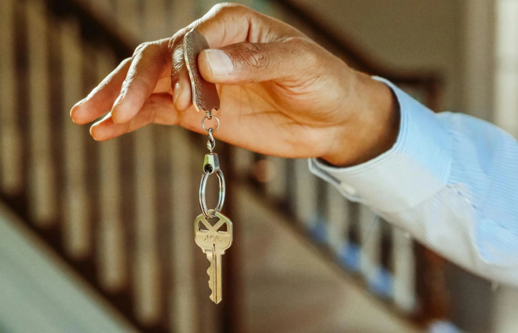 A retiree holding keys in front of a rental property