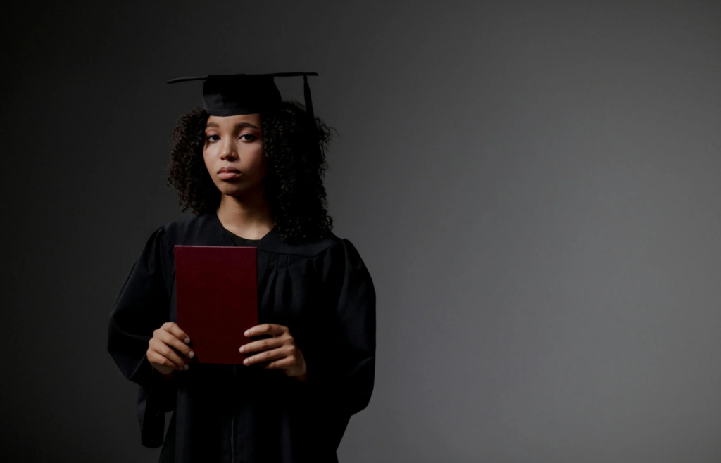 A woman in academic regalia holding a red book