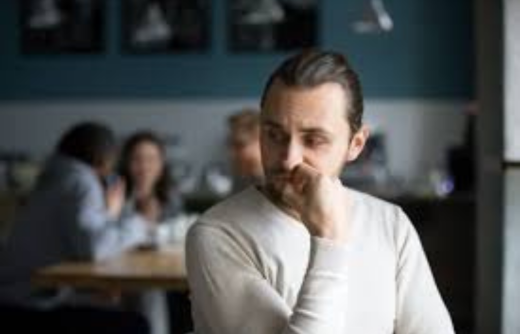 A man sitting alone in a café, observing groups of people