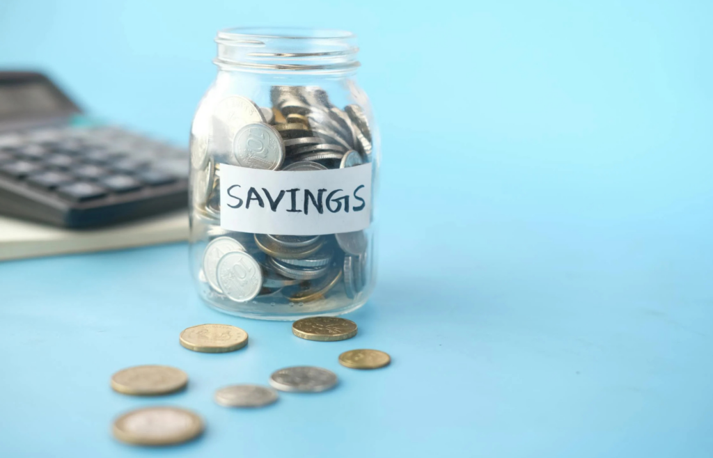 A person stacking coins into a savings jar