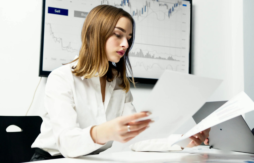 A woman in white dress shirt holding pieces of paper