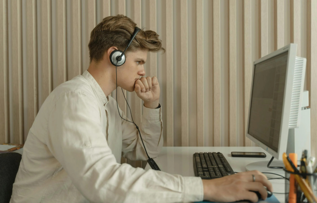 A person staring blankly at a computer screen in a cubicle