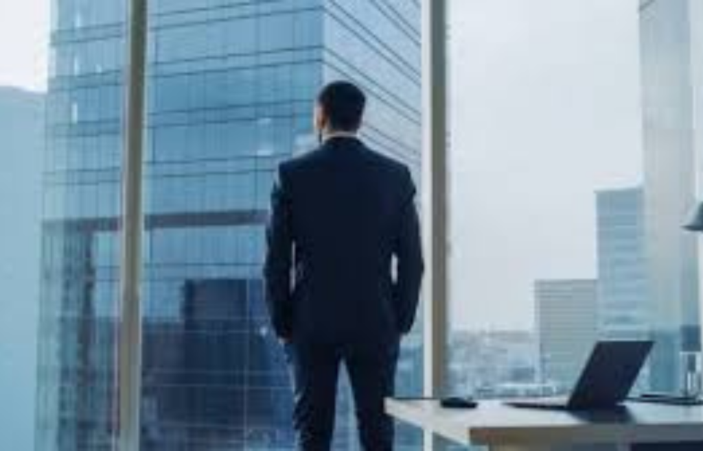 A person looking out of an office window, imagining a personal business venture