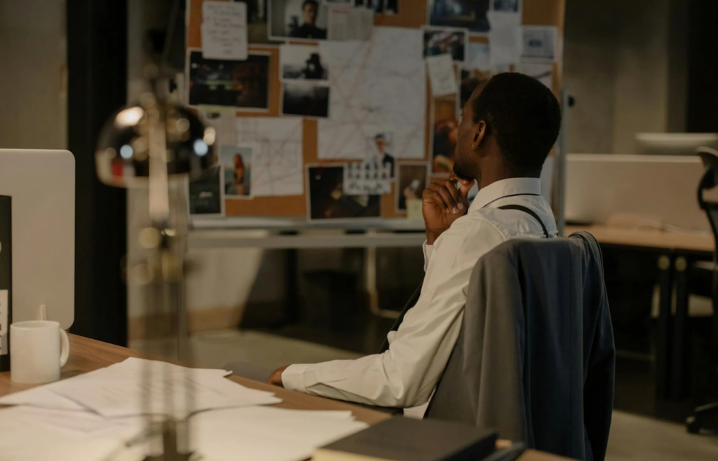 An individual working late in a dark office while family photos sit on the desk
