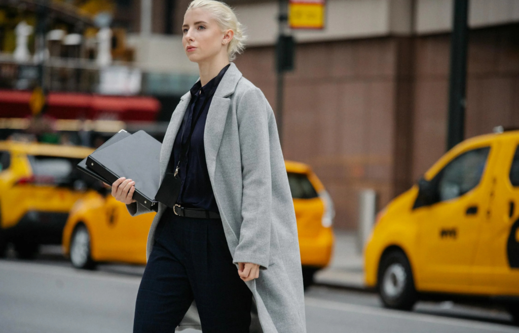 Serious businesswoman with folders crossing busy road