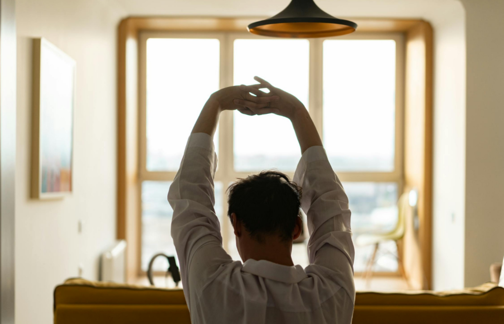 A person stretching by a window with morning sunlight streaming in