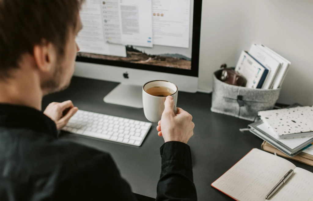 A person working at a desk and a cup of tea