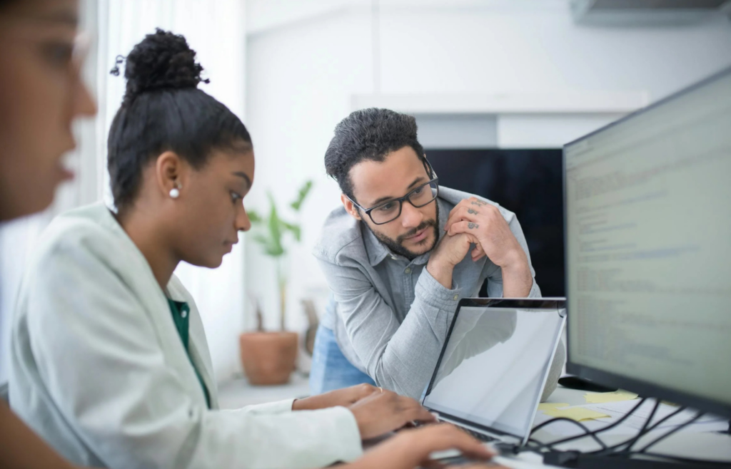A manager closely monitoring an employee's computer screen