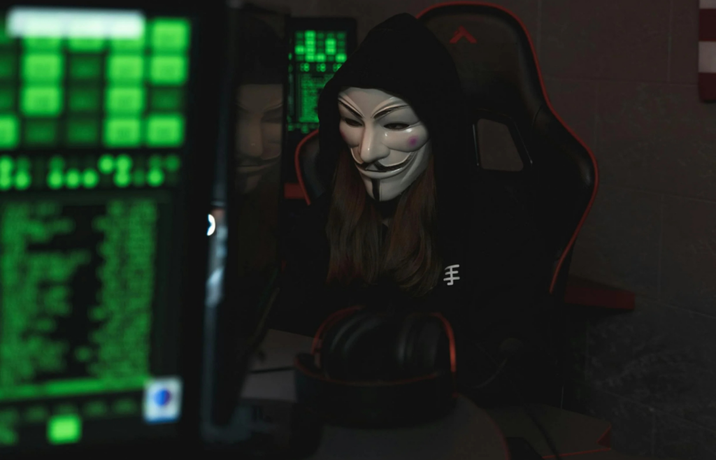 A hacker-style setup with green code and a smiling person in a hoodie