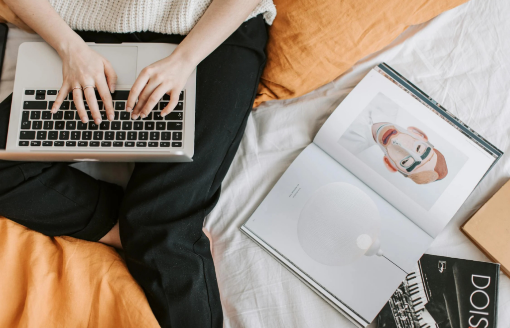 Unrecognizable woman typing on laptop in bed