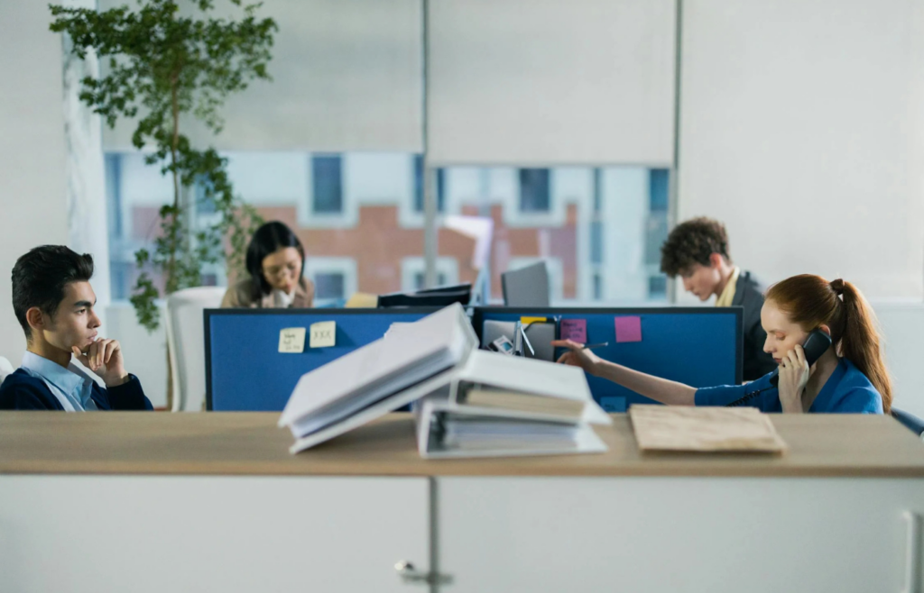 A bustling open-plan office with employees at closely arranged desks