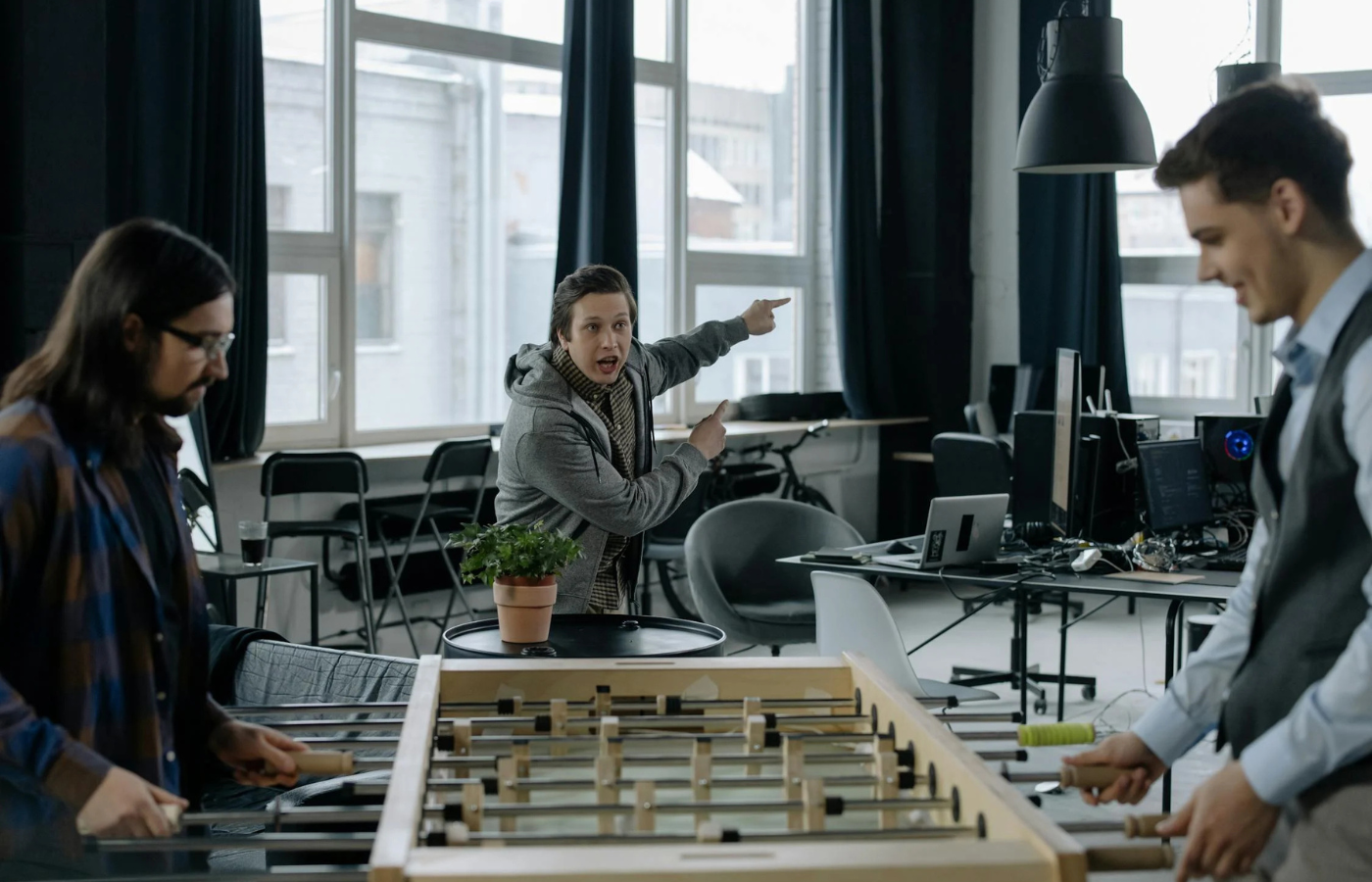 Coworkers playing foosball while colleague points animatedly