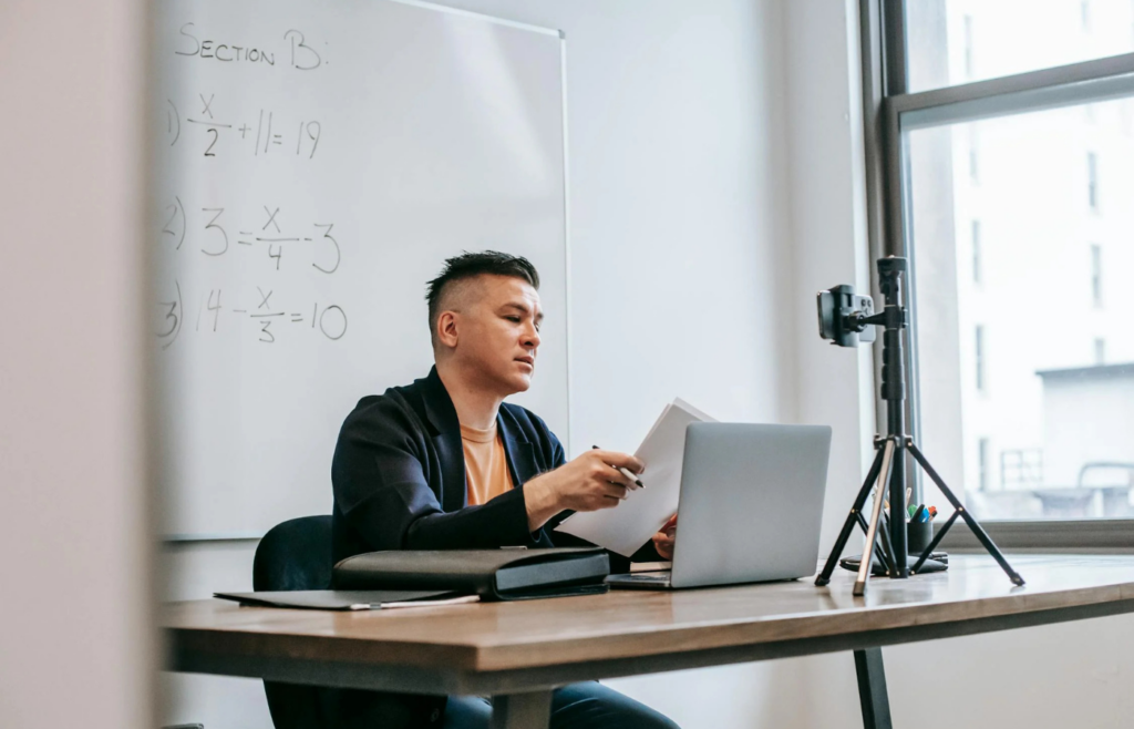 A person recording a lesson with a whiteboard and camera setup