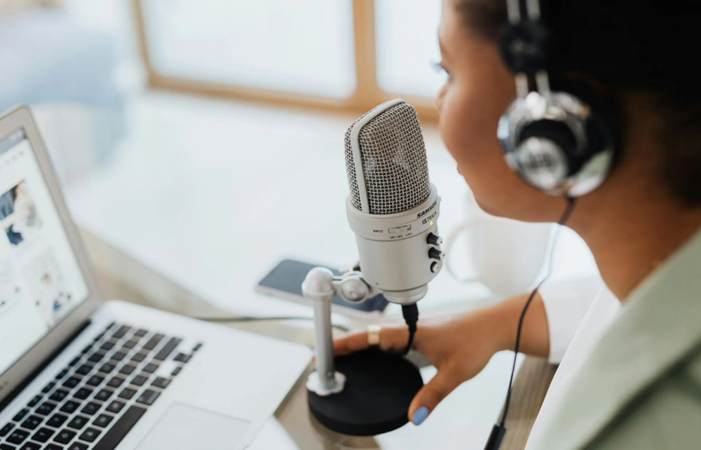 A podcast host in a recording studio with a mic and laptop