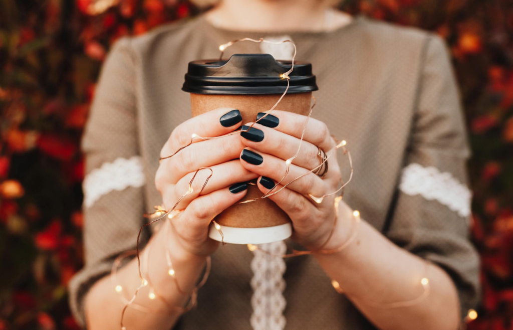 A person holding a takeaway coffee cup while commuting