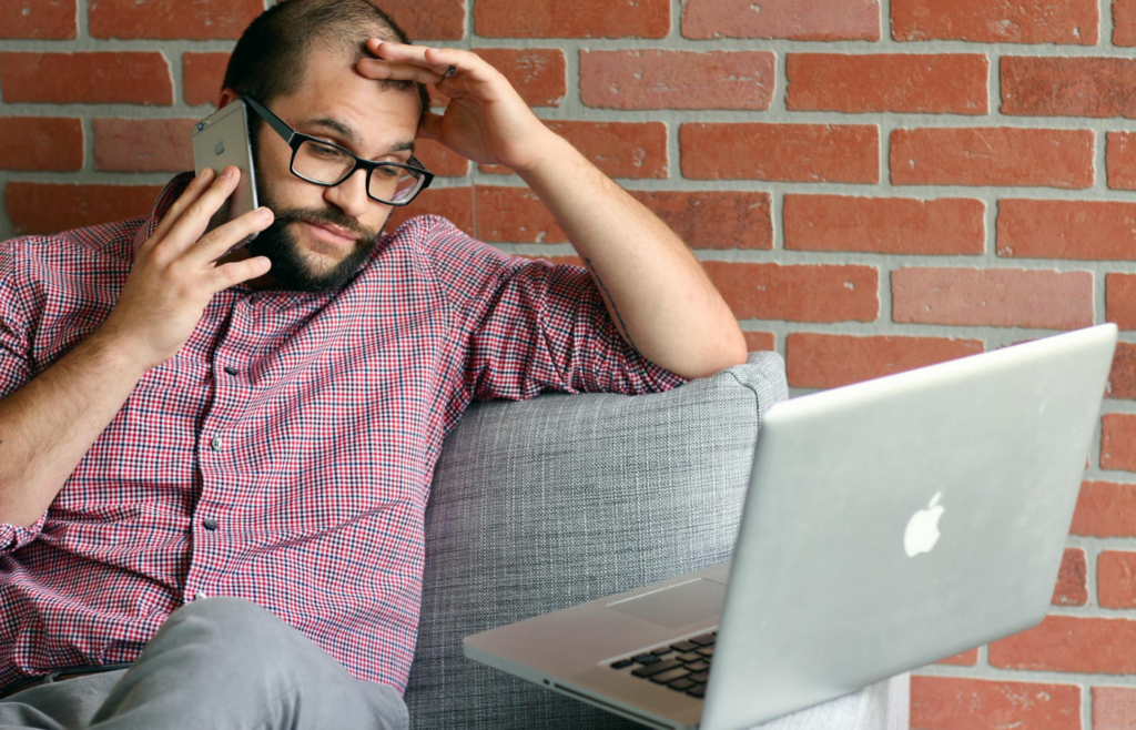 A frustrated person on a call while others joke around