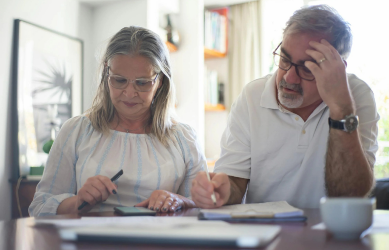 An elderly couple reviewing medical bills with concern