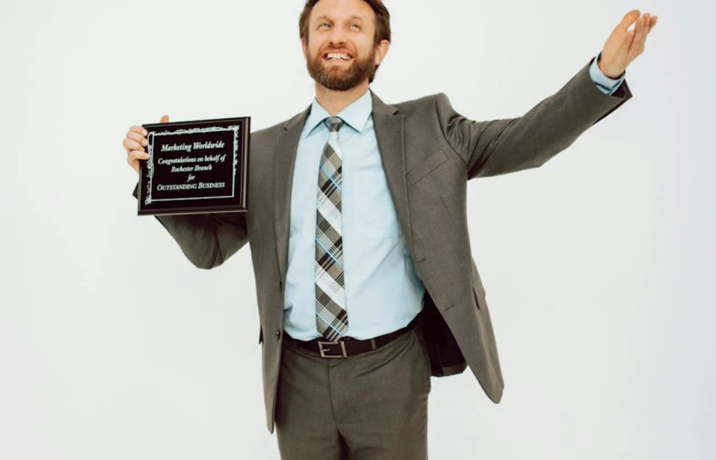 An employee holding a 'Job Well Done' certificate with no signature