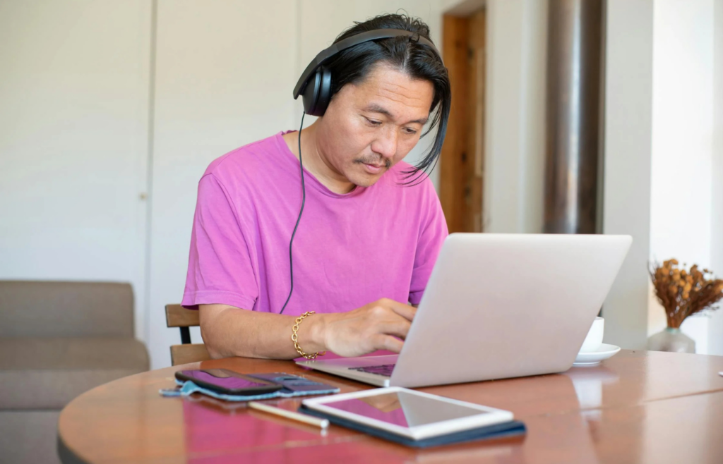 A professional working on a laptop in a coffee shop with headphones on