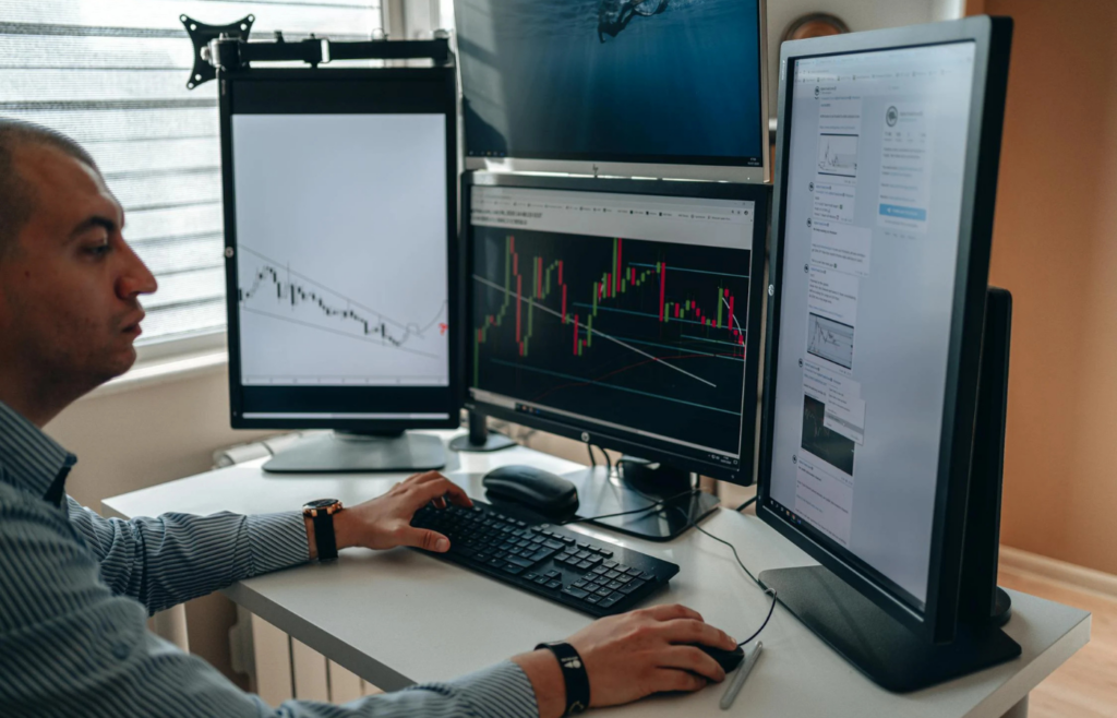 A person staring at multiple computer monitors filled with stock charts
