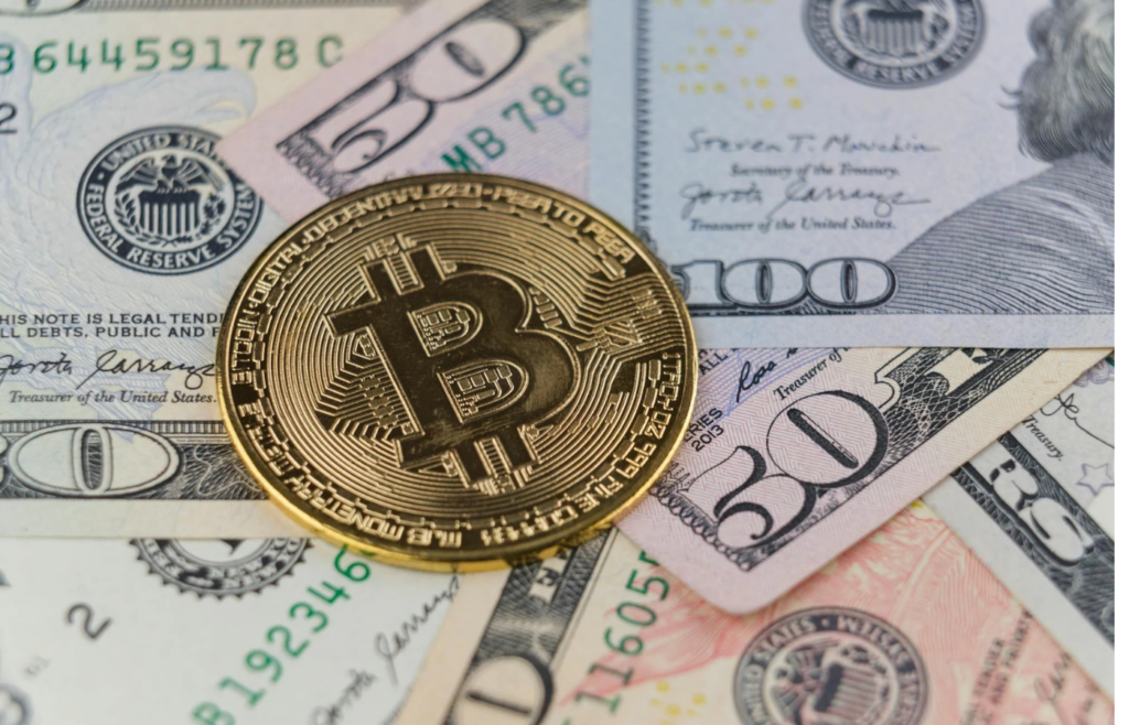A shiny Bitcoin coin resting on a pile of US dollars