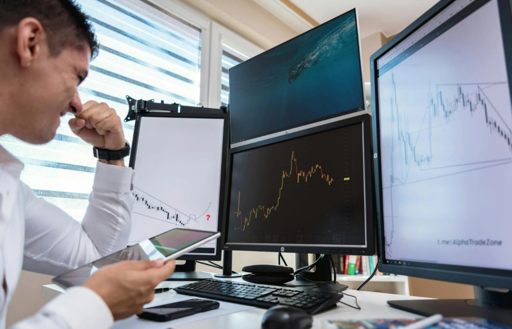 A stock trader staring at multiple screens with worried expressions