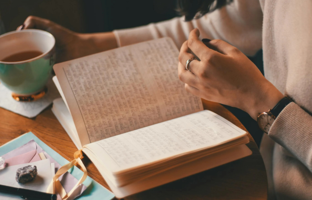 A person writing in a planner with a cup of coffee nearby