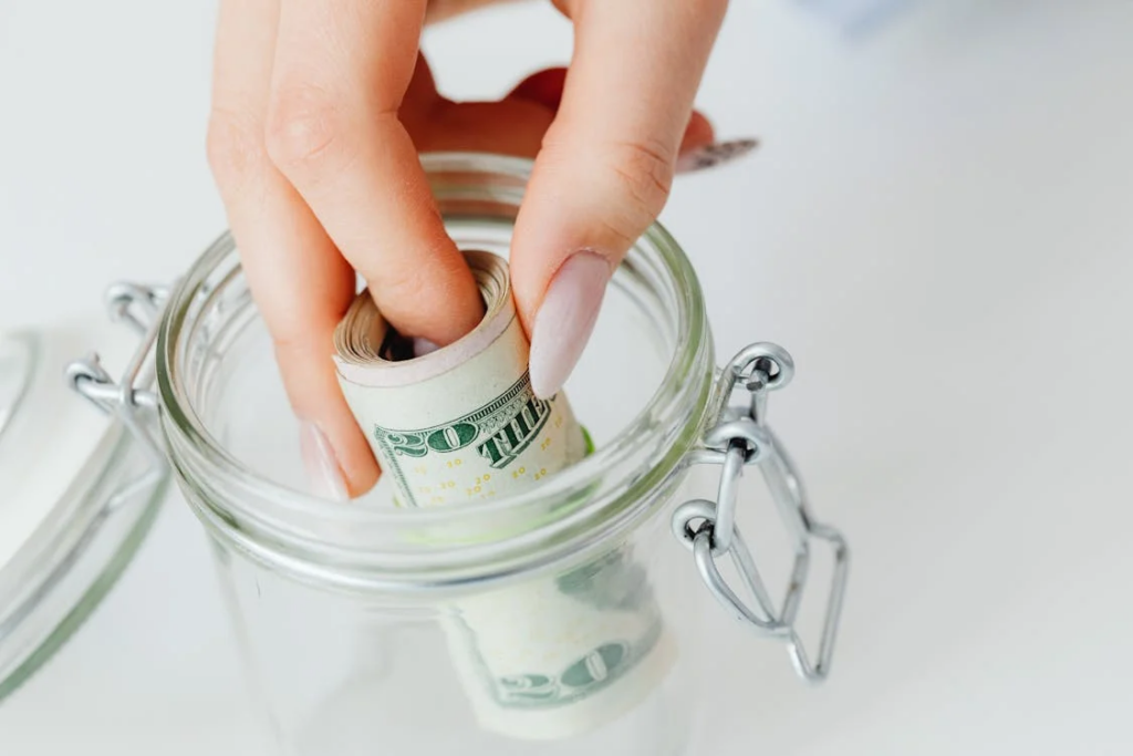 Close-up shot of a person saving money in the glass jar