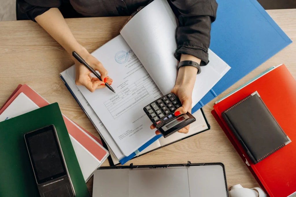 A person examining financial documents with a calculator