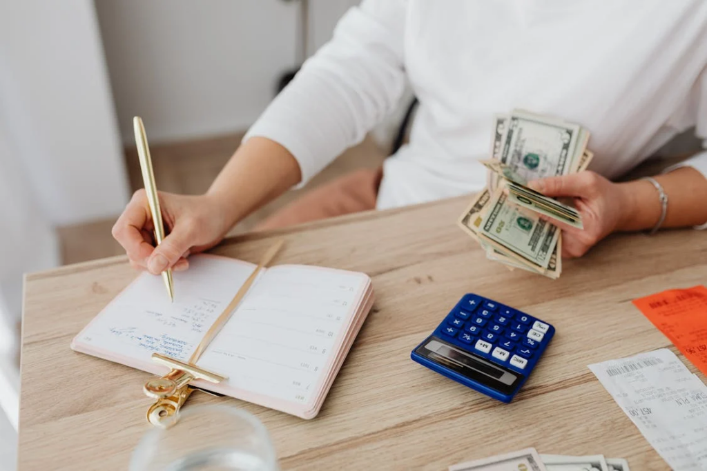 Person writing on a notebook while holding money