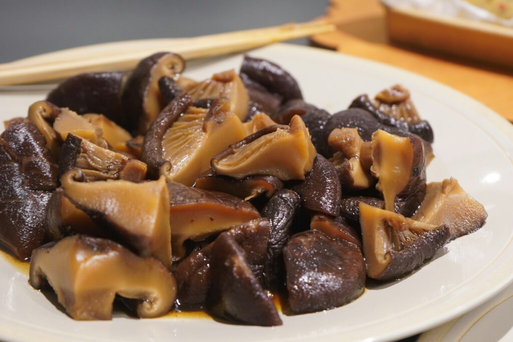A plate of cooked shiitake mushrooms with sauce