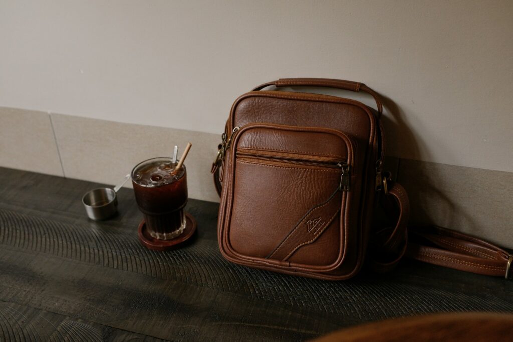 Brown leather bag with a drink and ashtray.