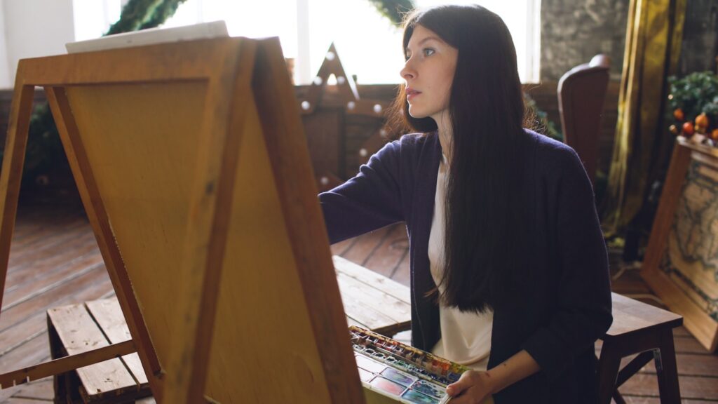 Young woman painting on an easel in a studio.