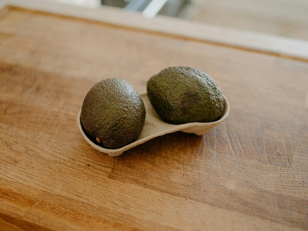 Two avocados in a holder on a wooden surface