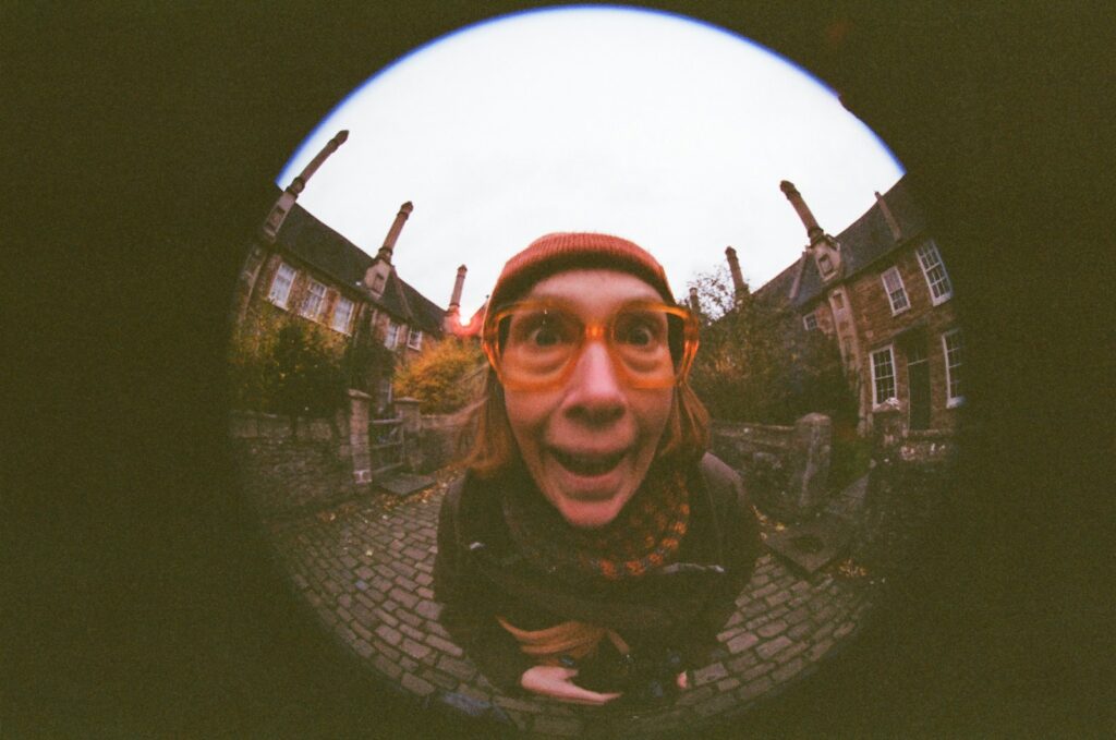 Woman with orange glasses makes funny face through peephole