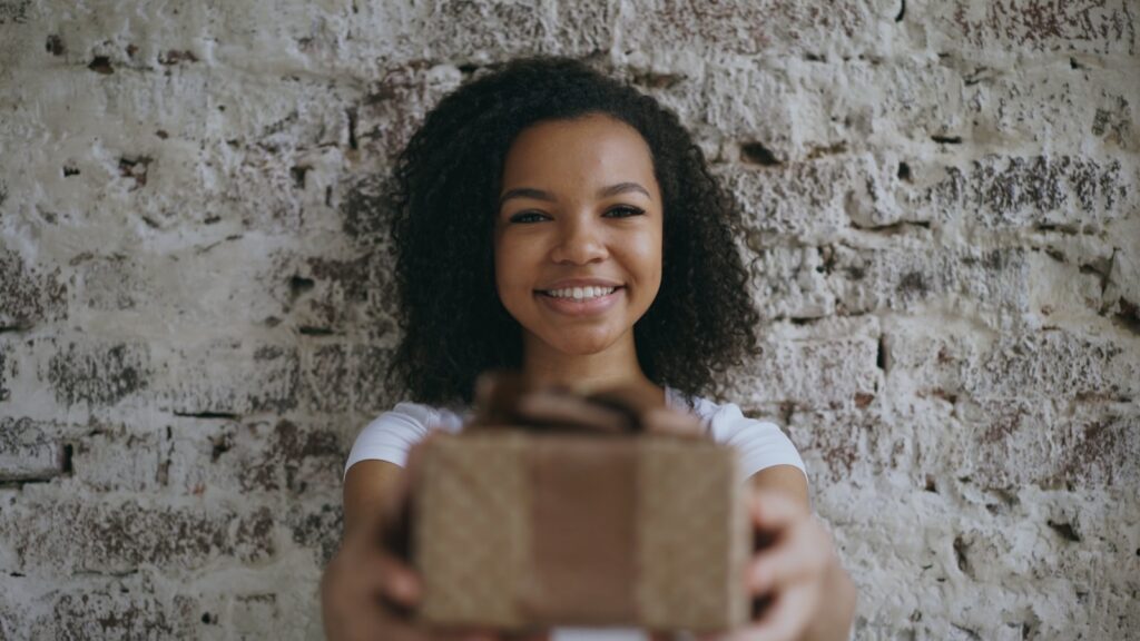 Young woman offering a gift with a smile.