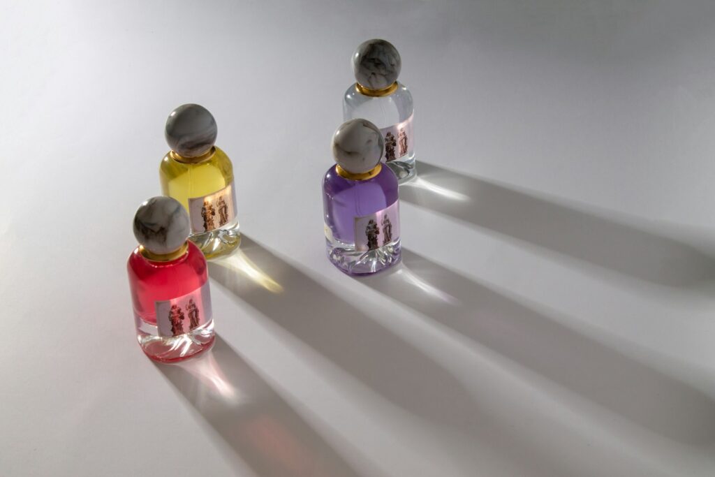 Four colorful perfume bottles casting long shadows