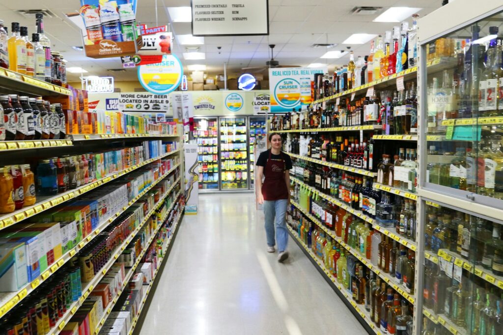 A person walks down a brightly lit grocery store aisle.