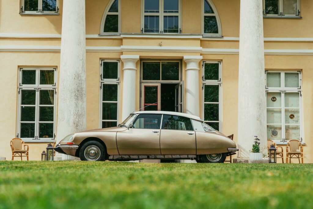 brown sedan parked beside white concrete building during daytime