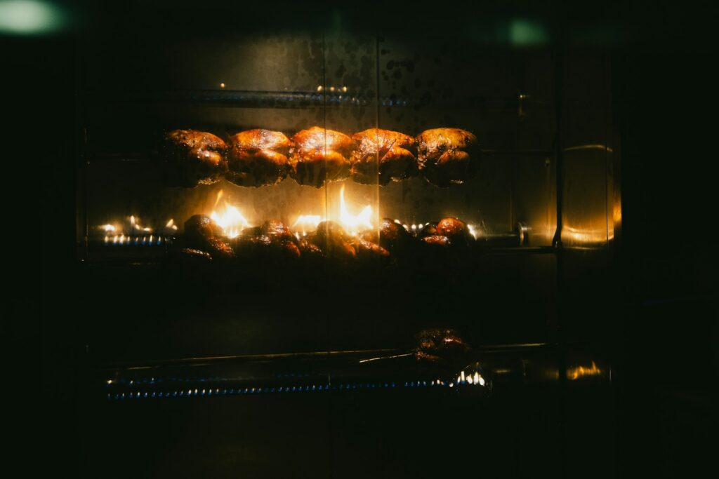 Chickens rotating on a rotisserie over flames